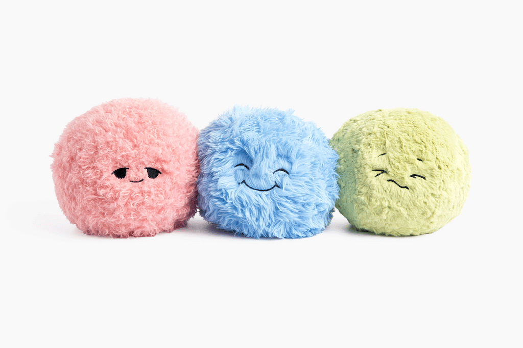 The Pink, Blue, and Green Hug Ball next to each other on a white background alternating faces in a quick video.