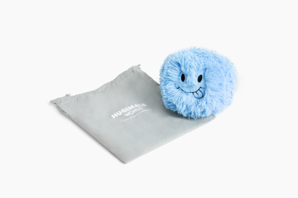 Photo showing a Blue Hug Ball in the forefront with its "Silly" expression facing us, and a Hugimals World branded light gray drawstring gift bag laying down behind it.